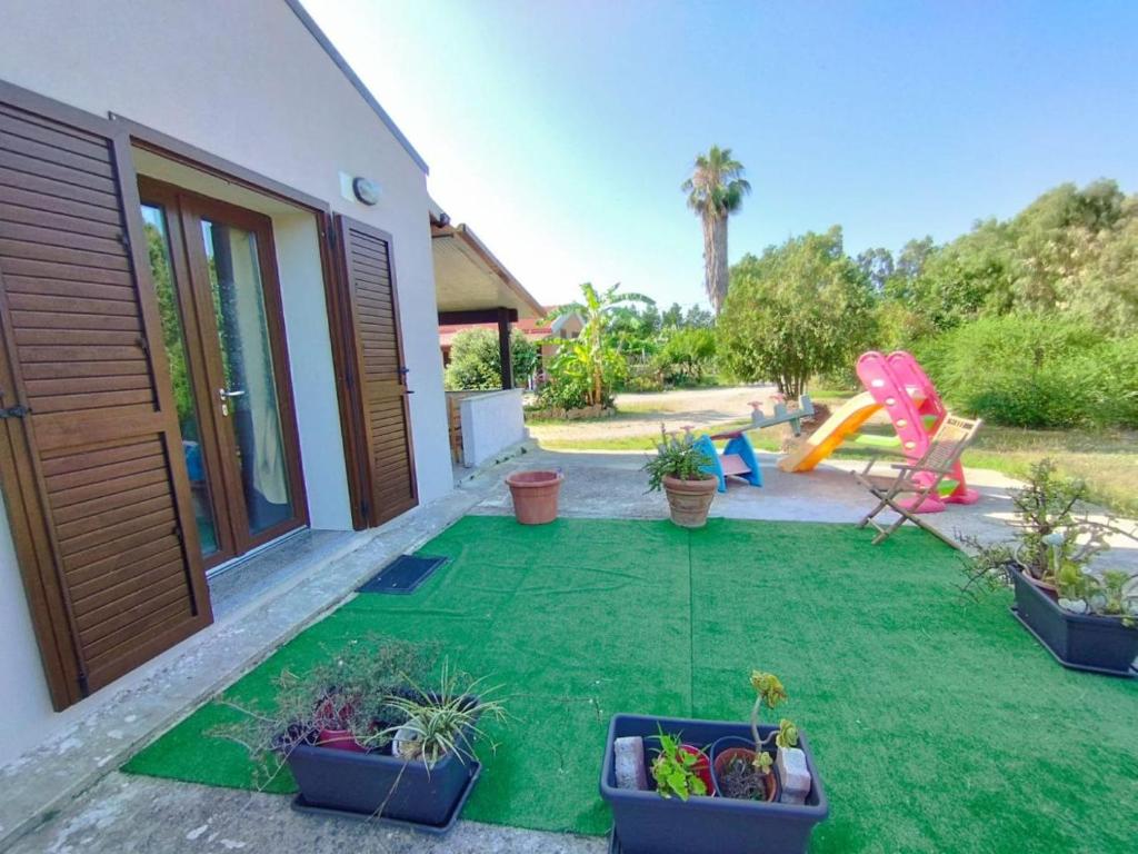 un cortile con un prato verde e un parco giochi di Camera Serraona ad Alghero