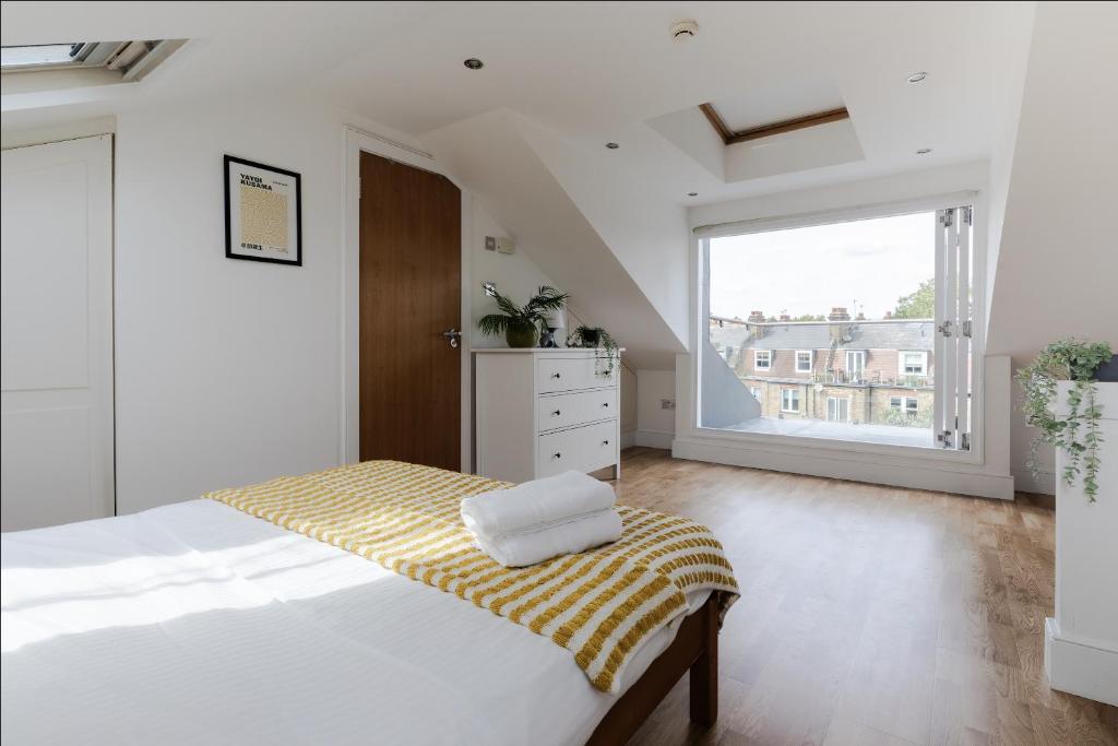 - une chambre blanche avec un lit et une grande fenêtre dans l'établissement Spacious 3 Bedroom Regents Park Apartment, à Londres