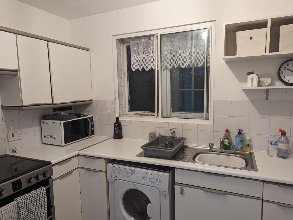 a kitchen with a washing machine and a sink at Modern ground floor flat in Cranford