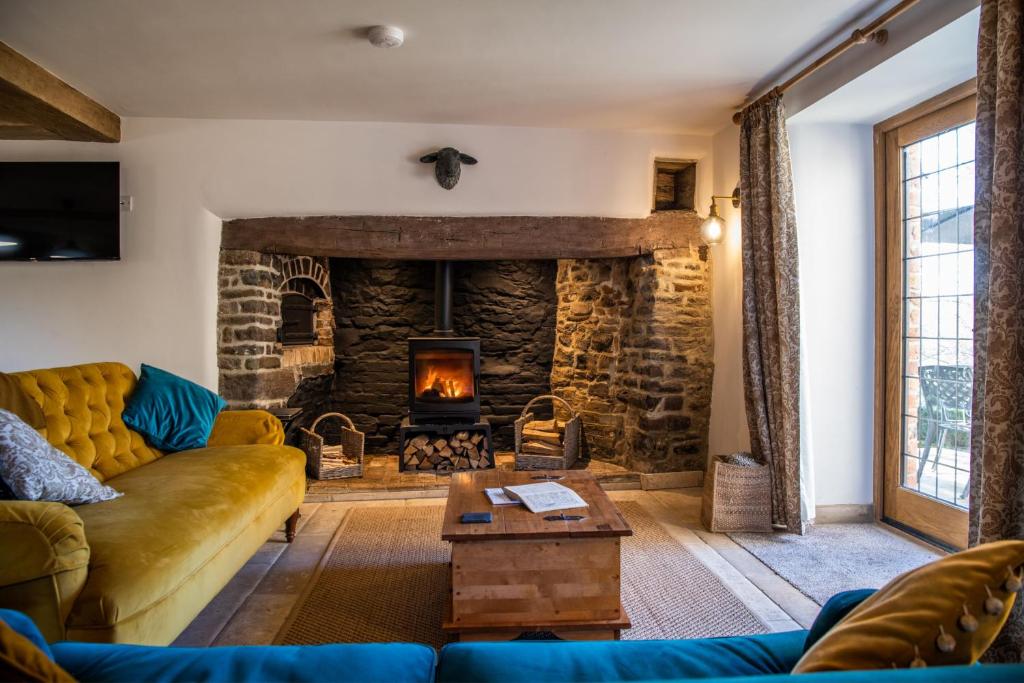 a living room with a couch and a stone fireplace at Keepers Lodge in Knowstone