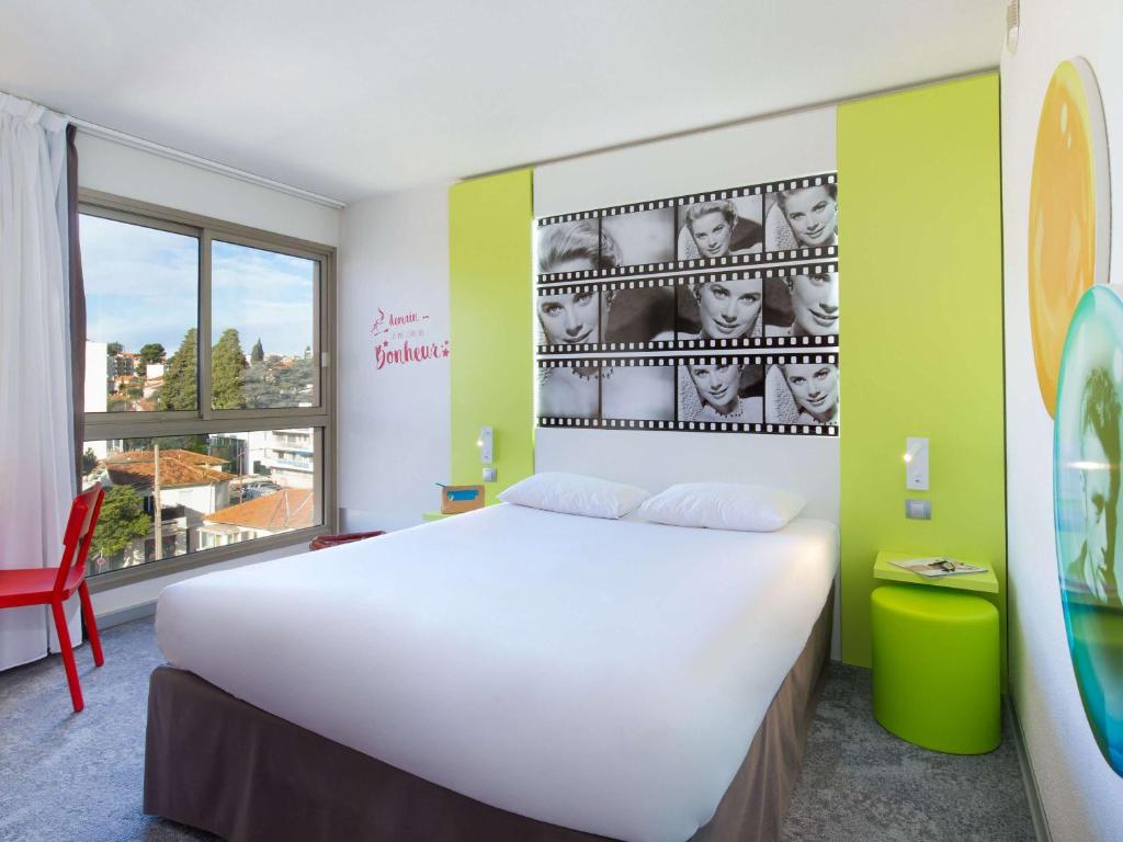 a bedroom with a large white bed and a window at ibis Styles Cannes Le Cannet in Cannes