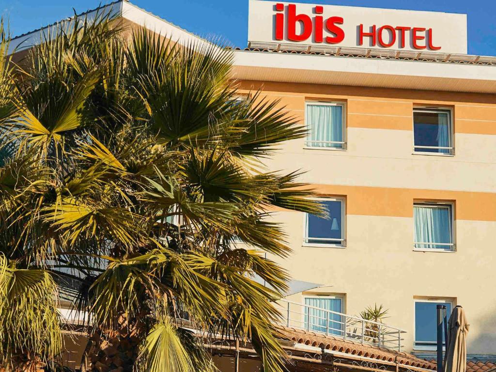 a hotel with a palm tree in front of a building at ibis La Ciotat in La Ciotat