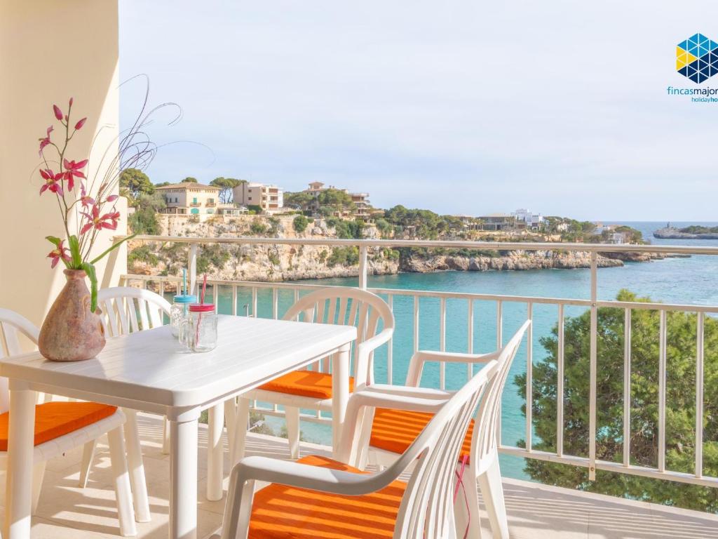 biały stół i krzesła na balkonie z widokiem na ocean w obiekcie Vistamar holiday home w Porto Cristo