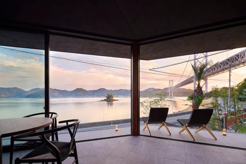 尾道市にあるSeaside Villa SEEN Deep Seaの橋の景色を望む客室で、テーブルと椅子が備わります。
