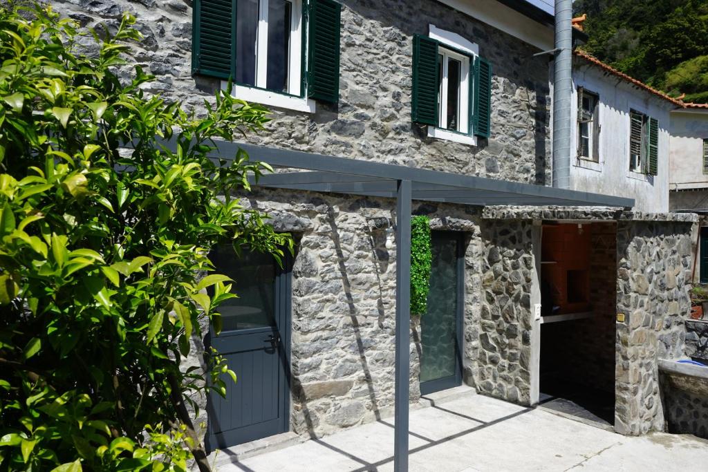 een stenen huis met groene luiken en een garage bij Casa do Lombo in Machico