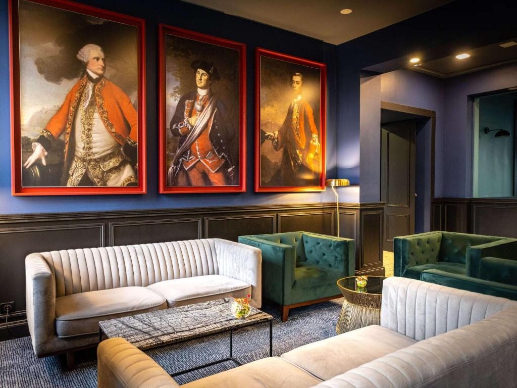 - un salon avec deux canapés et des peintures murales dans l&#39;établissement Hôtel Mercure Rochefort La Corderie Royale, à Rochefort