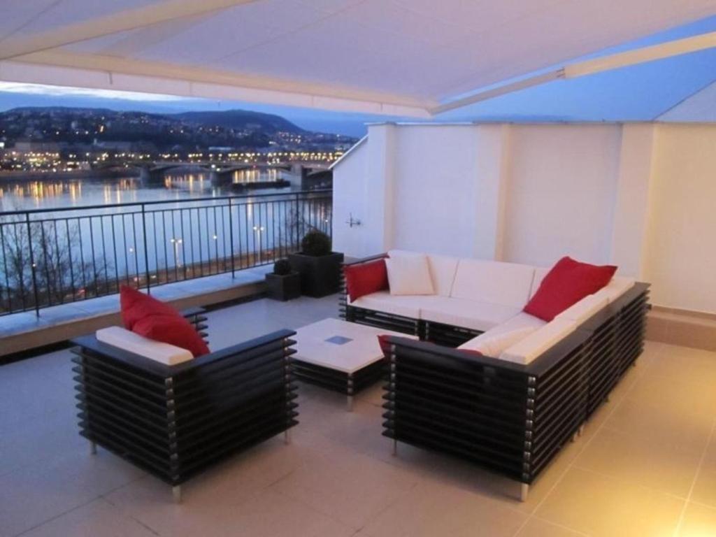 uma sala de estar com um sofá e cadeiras numa varanda em Penthouse mit Donaublick em Budapeste