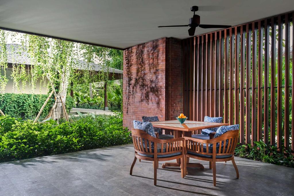 a patio with a wooden table and chairs at Andaz Bali - a Concept by Hyatt in Sanur