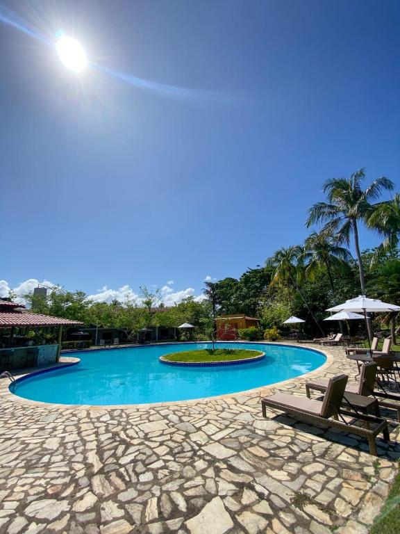 uma piscina com duas cadeiras e uma palmeira em Angá Beach Hotel em São Miguel dos Milagres