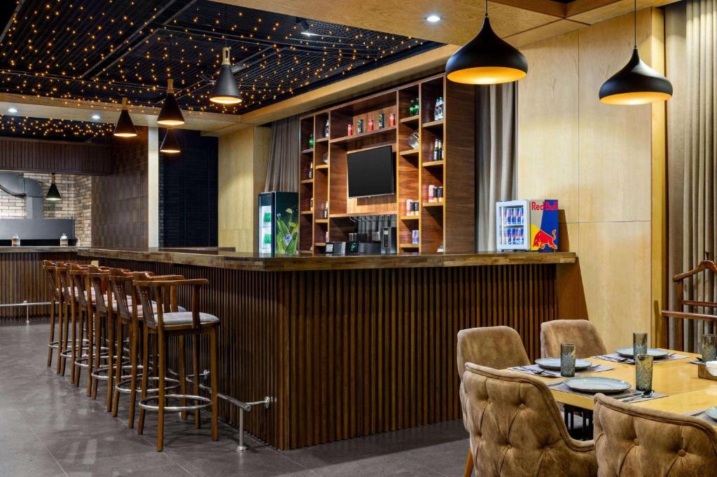a restaurant with a bar with chairs and tables at Wyndham Garden Tashkent in Tashkent