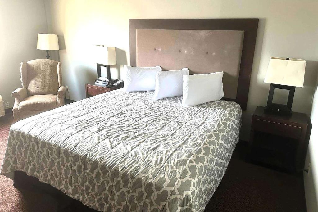 a hotel room with a bed and a chair at Super 8 by Wyndham Fort Scott in Fort Scott