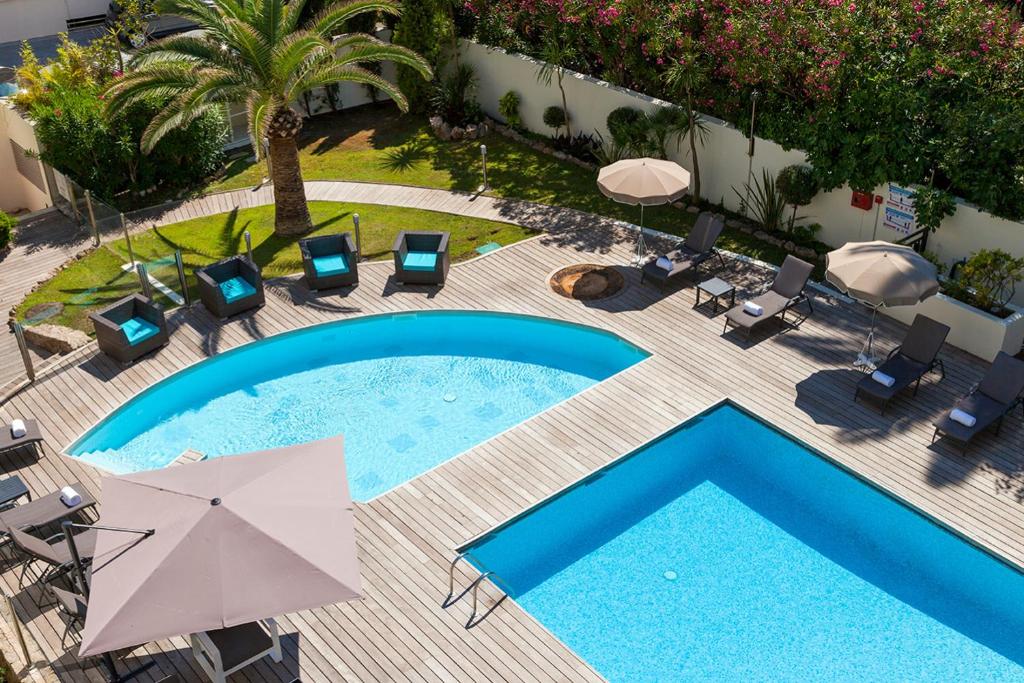 een uitzicht over een zwembad met stoelen en parasols bij Nehô Suites Cannes Croisette in Cannes