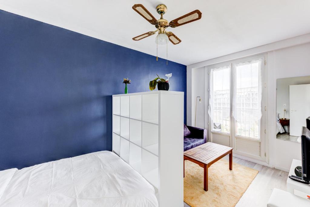 1 dormitorio con pared de acento azul y ventilador de techo en Le Central tout équipé !, en Toulouse