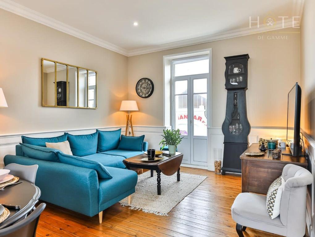 een woonkamer met een blauwe bank en een klok bij Chaleureux logement-centre ville-proche gare-plage in Les Sables-dʼOlonne