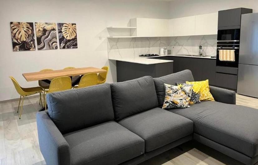 a living room with a gray couch and a kitchen at St Julians New 3 Bedroom Luxury Apartment in St. Julianʼs