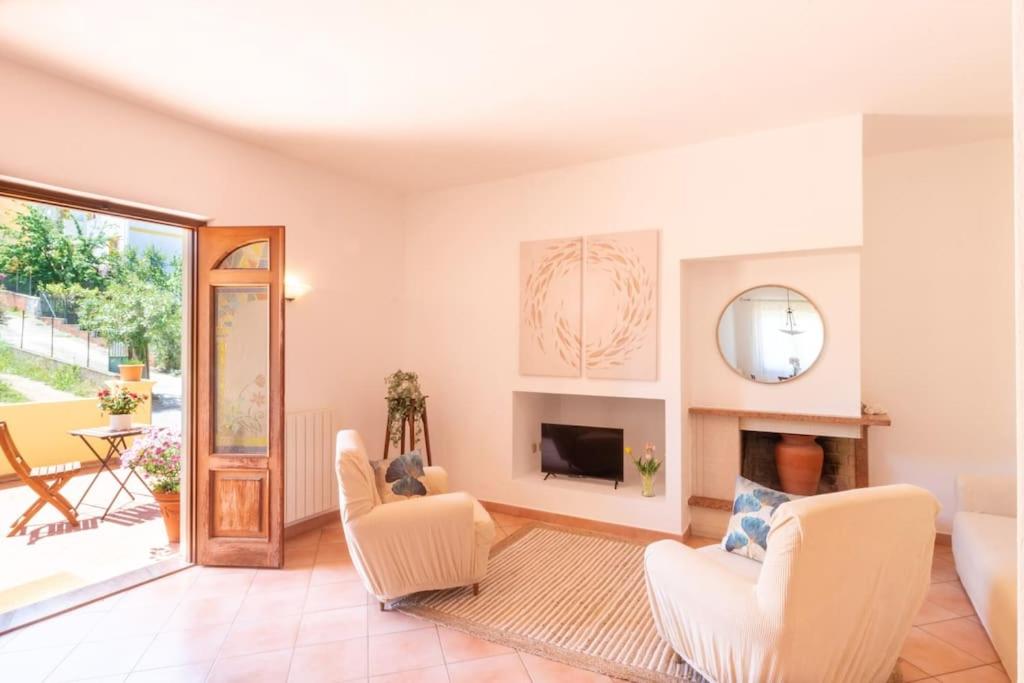 a living room with white furniture and a fireplace at Su Trigu, ground floor in Bari Sardo