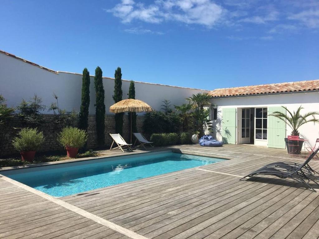 une cour arrière avec une piscine et une terrasse en bois dans l'établissement Villa idéale pour deux familles qui cohabitent, à Sainte-Marie de Ré
