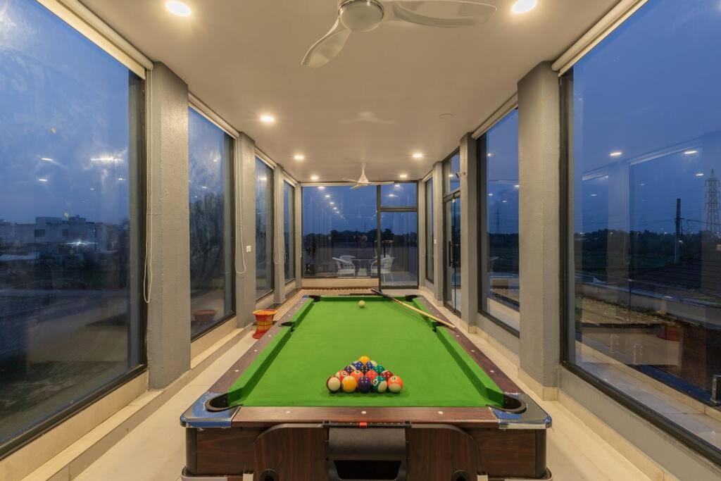 a pool table in a room with large windows at Tarshal Outhouse to relax in Jaipur in Jaipur