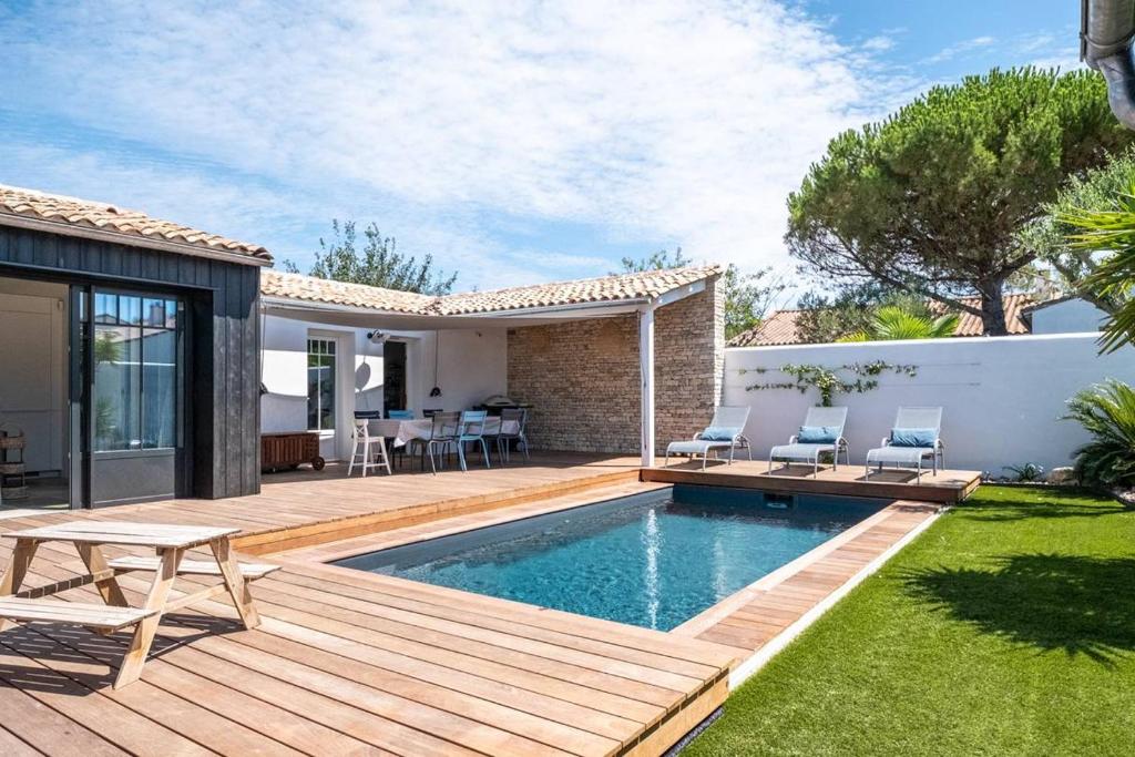 une arrière-cour avec une terrasse en bois et une piscine dans l'établissement Maison familiale rénovée avec piscine quartier de la Cible, à Saint-Martin-de-Ré