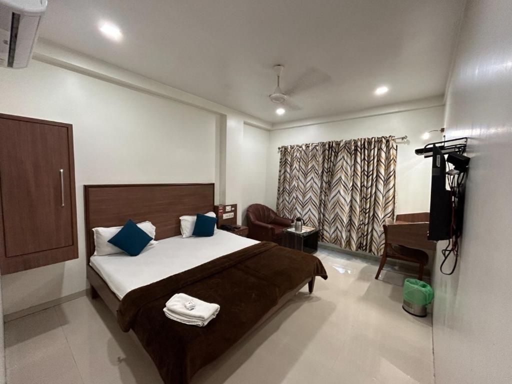 een slaapkamer met een bed, een bureau en een televisie bij Hotel Horizon Vapi in Vapi