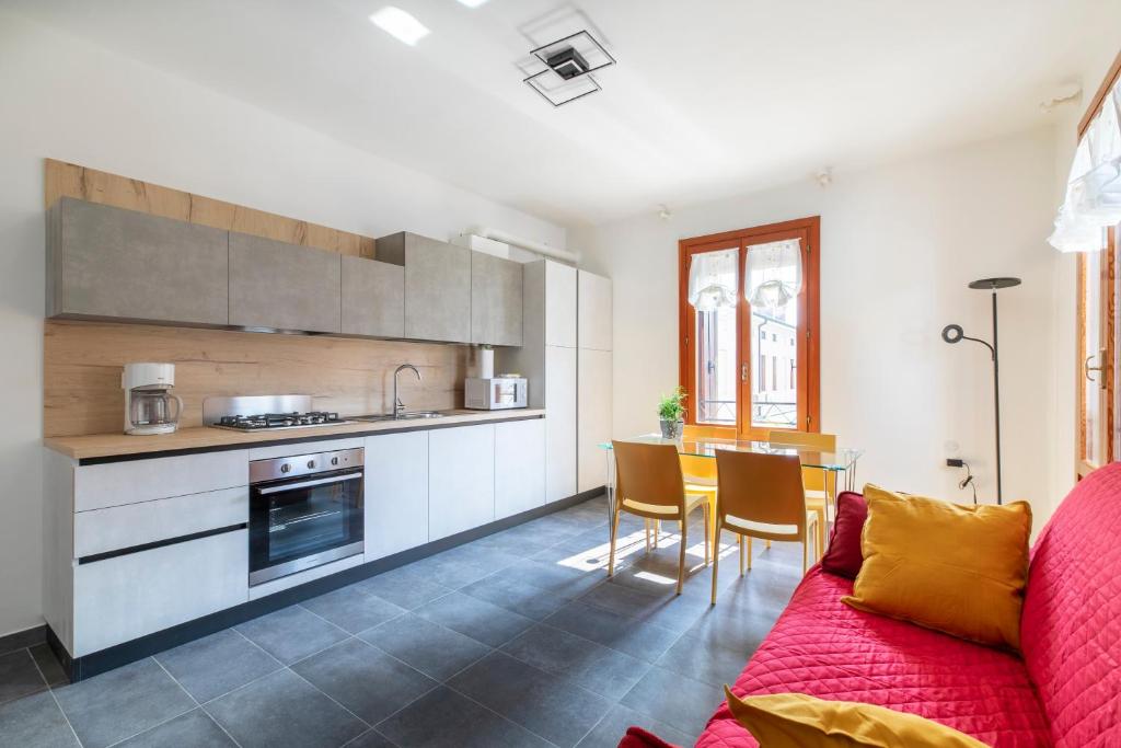 sala de estar con sofá rojo y cocina en Minuetto Apartment - 2 bedrooms, en Vicenza