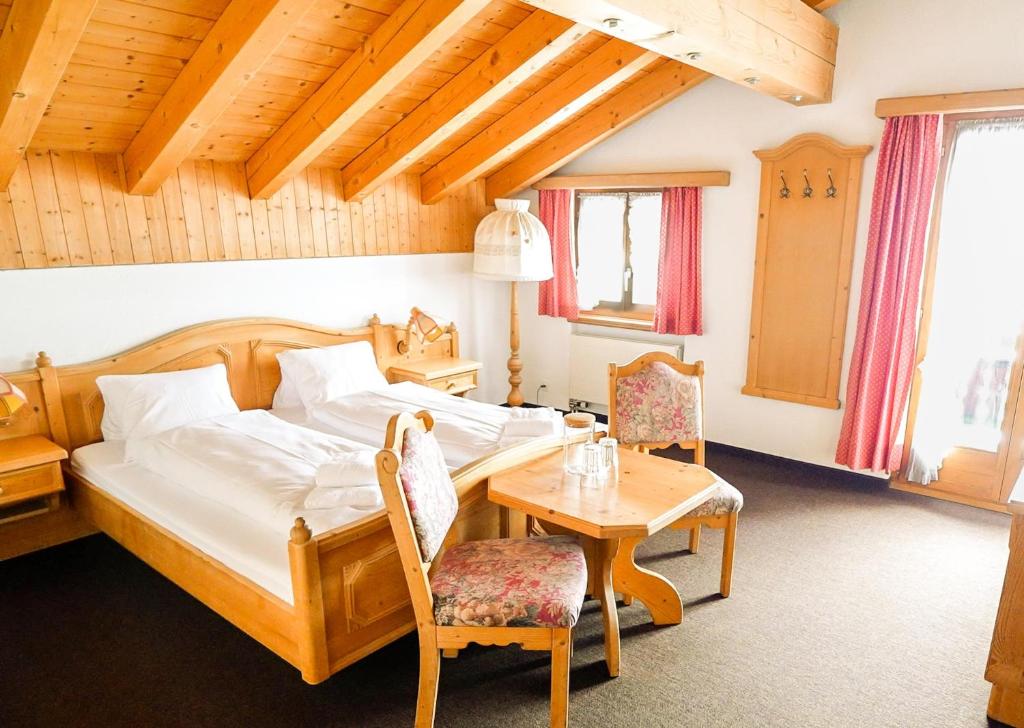 een slaapkamer met een bed en een tafel en stoelen bij Hotel Postigliun Sedrun in Sedrun
