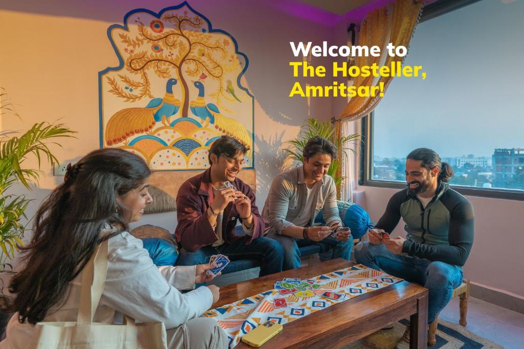 un grupo de personas sentadas alrededor de una mesa en The Hosteller Amritsar, en Amritsar
