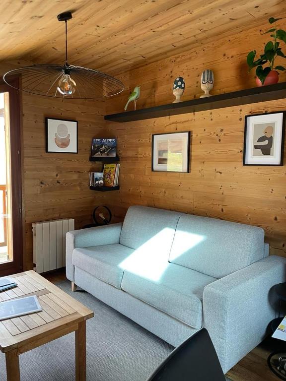 - un salon avec un canapé bleu et des murs en bois dans l'établissement 40m2 au pied des pistes Hauteluce les saisies 4 à 6 personnes, à Hauteluce