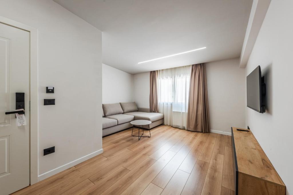 a living room with a couch and a television at Relax Inn Hotel Durres in Durrës