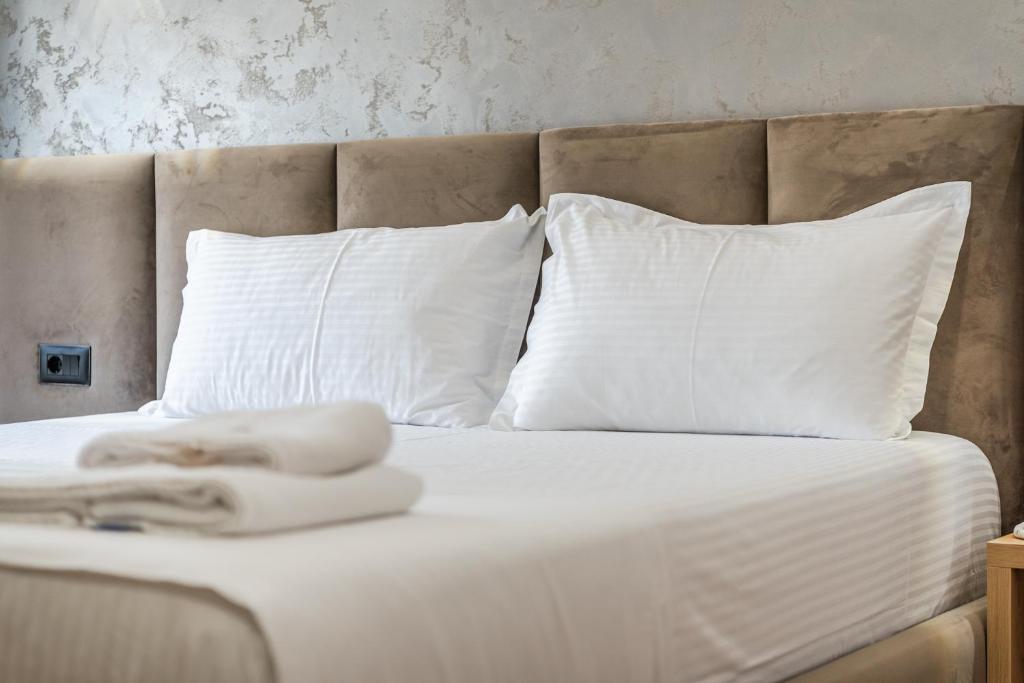 a bed with white pillows and white towels on it at Relax Inn Hotel Durres in Durrës