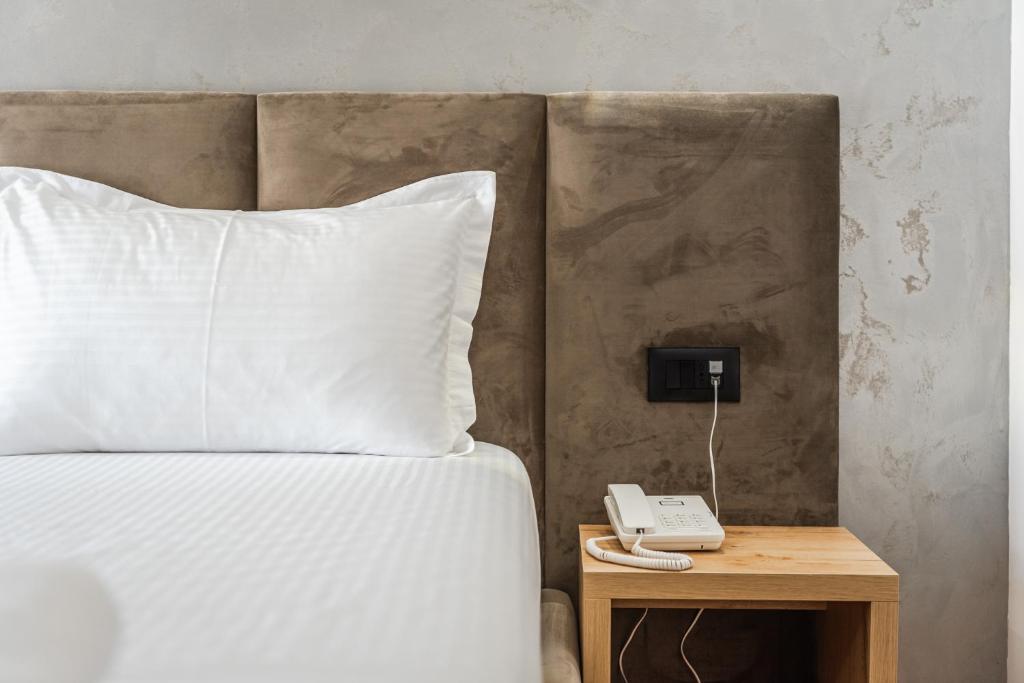 a bed with a white pillow and a phone on a table at Relax Inn Hotel Durres in Durrës