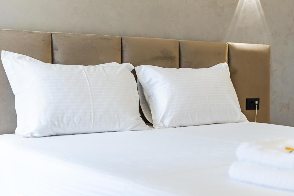 a bed with white pillows on top of it at Relax Inn Hotel Durres in Durrës