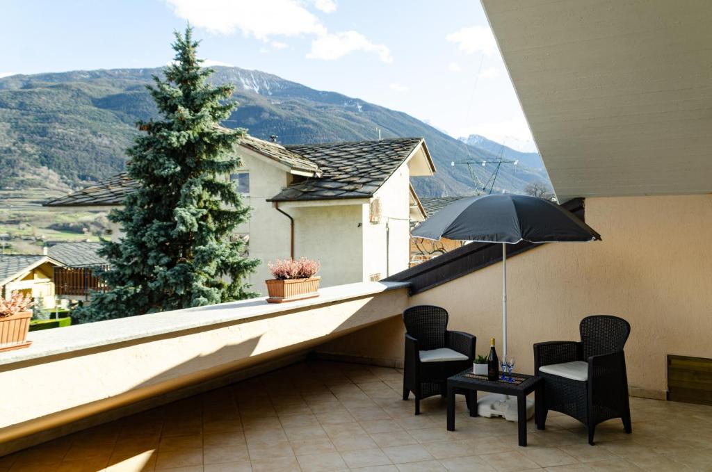 uma varanda com 2 cadeiras e um guarda-sol em Sarre Skyline Apartment - Relax in Valle d'Aosta em Aosta
