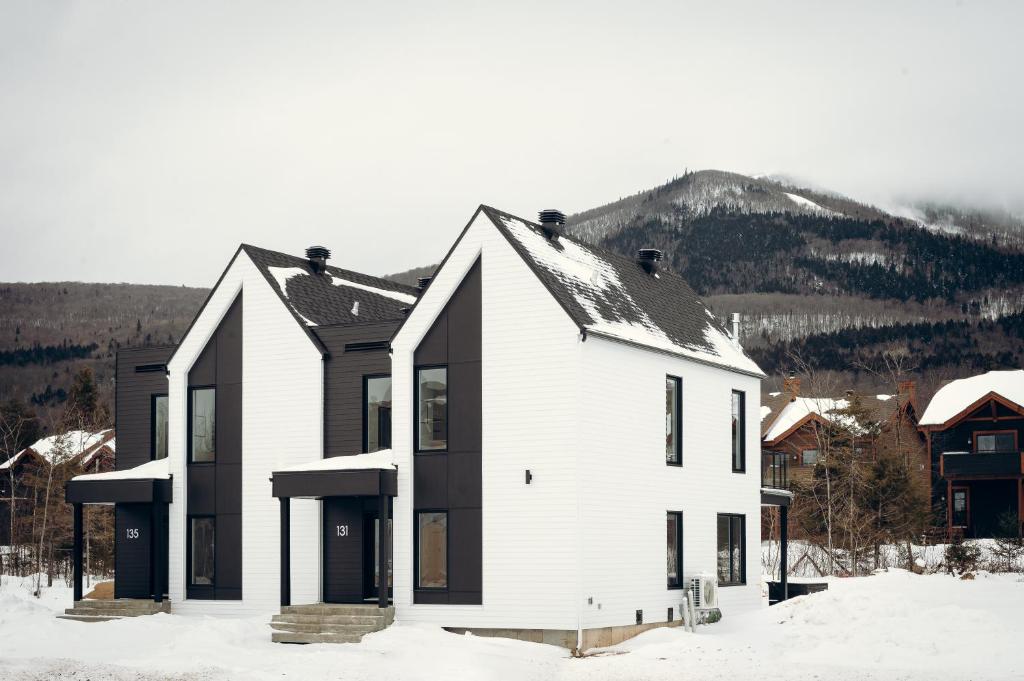 a house in the snow with a mountain in the background at Villas Perspective-Alphonse-Mont-Ste-Anne in Beaupré