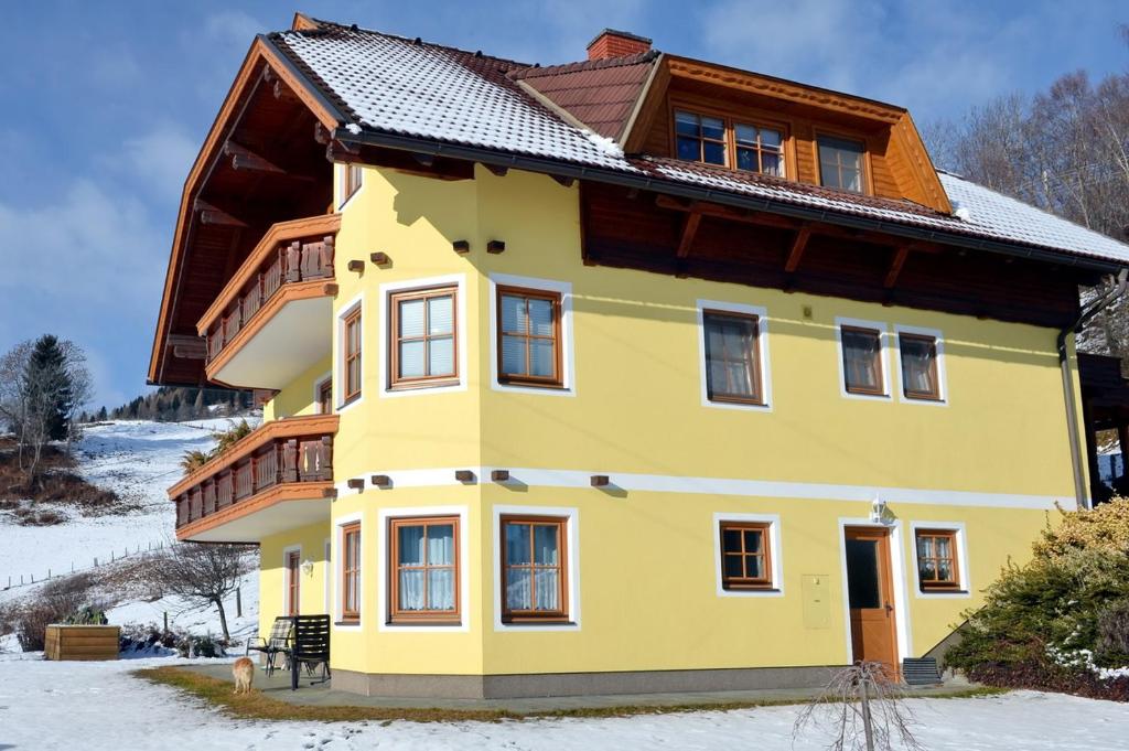 een geel huis met een bruin dak bij Haus Sonnenschein in Feldkirchen in Kärnten