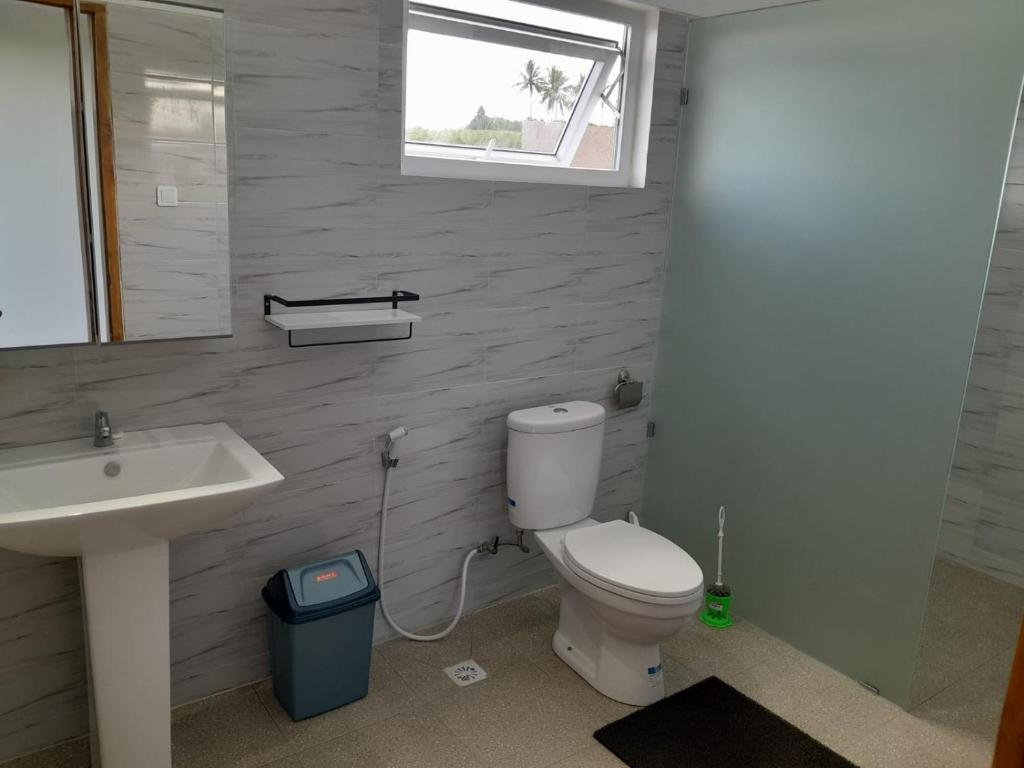 a bathroom with a toilet and a sink and a window at Villa bahagia in Jembrana