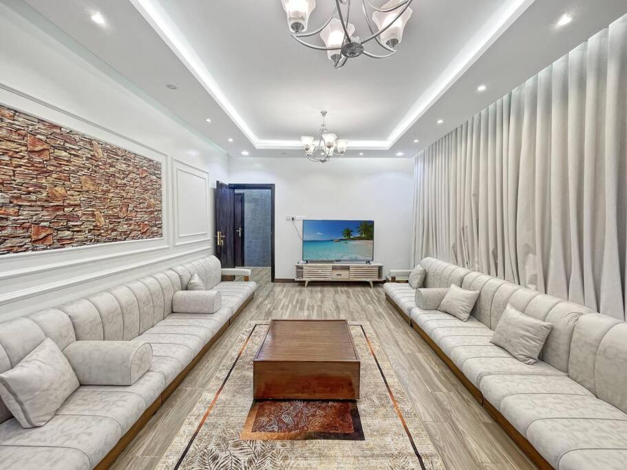 een woonkamer met een grote bank en een tv bij شقة خمس غرف علي طريق السودة in Abha