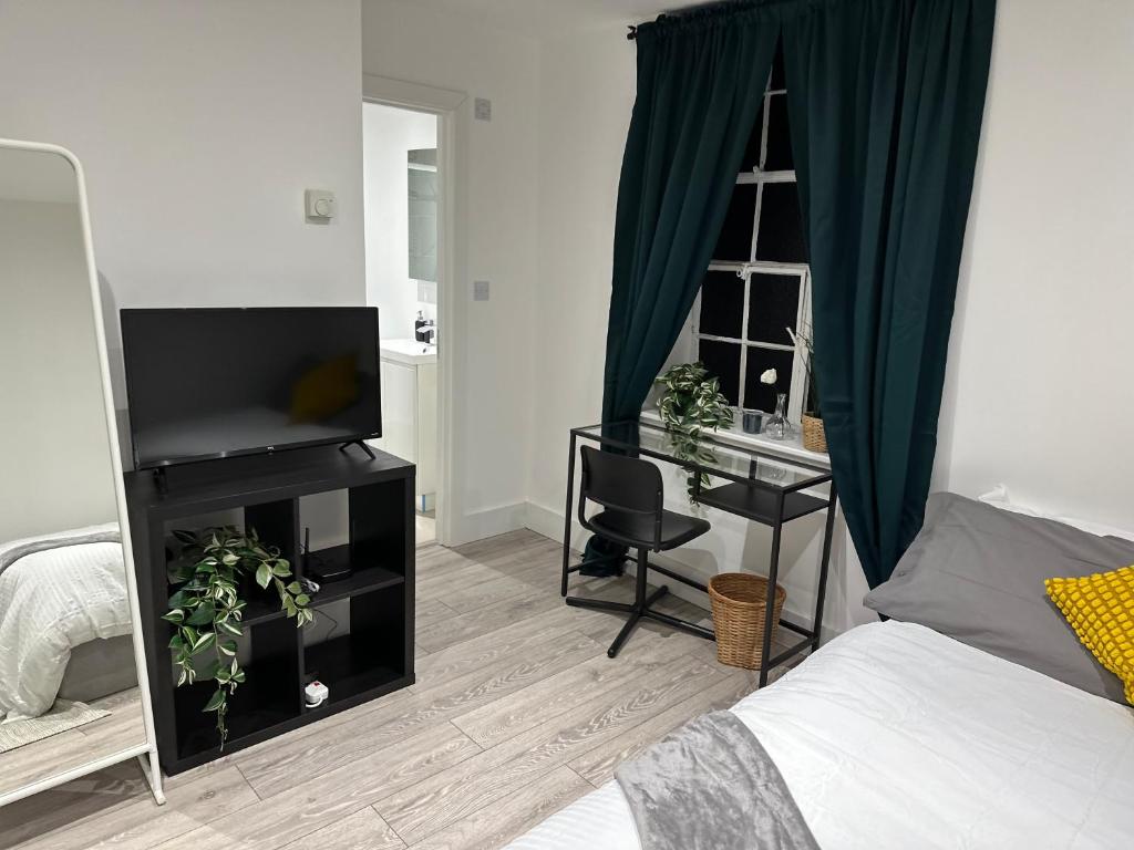 a bedroom with a bed and a desk with a television at Stunning One Room Apartment in Maidstone