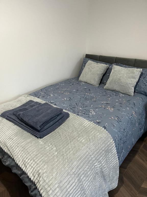 a bed with a blue blanket and pillows on it at Stylish and Spacious in Kettering