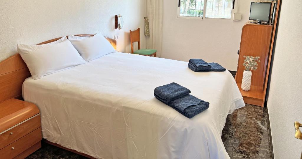 Un dormitorio con una cama blanca con toallas. en A 100m de la playa. 2 hab. A/C, en Alicante
