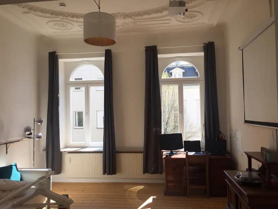ein Wohnzimmer mit 2 Fenstern und einem Schreibtisch in der Unterkunft Gründerzeitzimmer mit Bad in Bonn