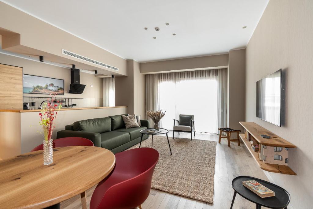 Open-plan living area with green sofa, round wooden dining table with red chairs, wall-mounted TV, and sliding glass doors at Maison Bucarest Apartments by Olala Homes in Bucharest