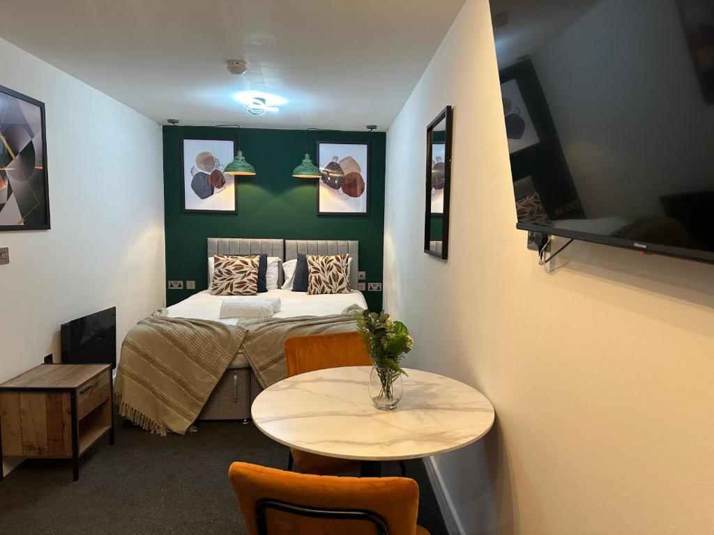 a bedroom with a bed and a table with chairs at Newark House Premium Apartments by DH ApartHotels in Peterborough