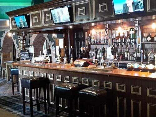 a bar with black stools in a room with a bar at The Sun Hotel in Warkworth