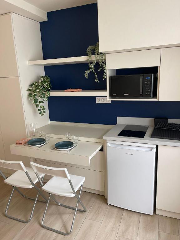 une cuisine avec deux chaises, une table et un four micro-ondes dans l'établissement Comme une chambre d’hôtel au cœur de Lyon, à Lyon