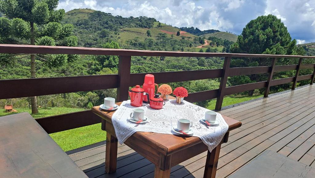 a table on a deck with a view of a mountain at Casa Sossego na Montanha in Campos do Jordão