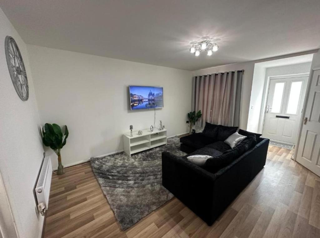 a living room with a black couch and a tv at Stunning 3-Bed House in Manchester in Manchester