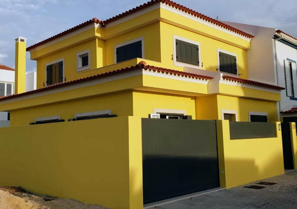 ein gelbes Haus mit einem Zaun davor in der Unterkunft Holidays Home Comporta in Comporta