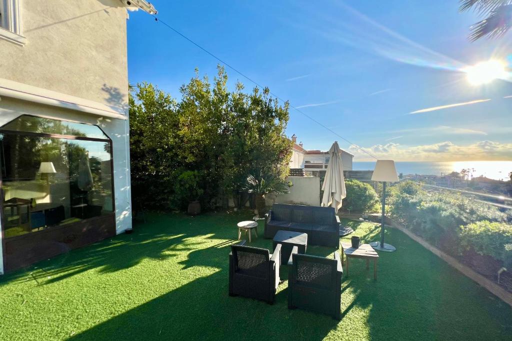 einen Hinterhof mit grünem Gras, einer Couch und einem Tisch in der Unterkunft Golfe Juan - Villa 4 people - Sea view - Garden in Vallauris
