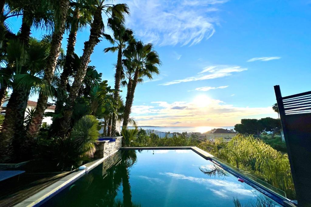 uma piscina com palmeiras e o oceano em Golfe-Juan - Villa 10 people - Private Pool - Parking em Vallauris